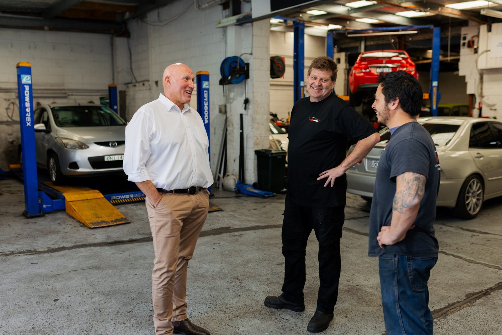 Michael Gencher talking with two mechanics in a local workshop